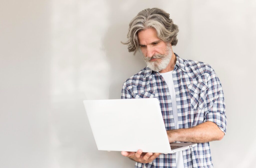 Tech Solutions for Seniors - man holding laptop using app for healthy brain