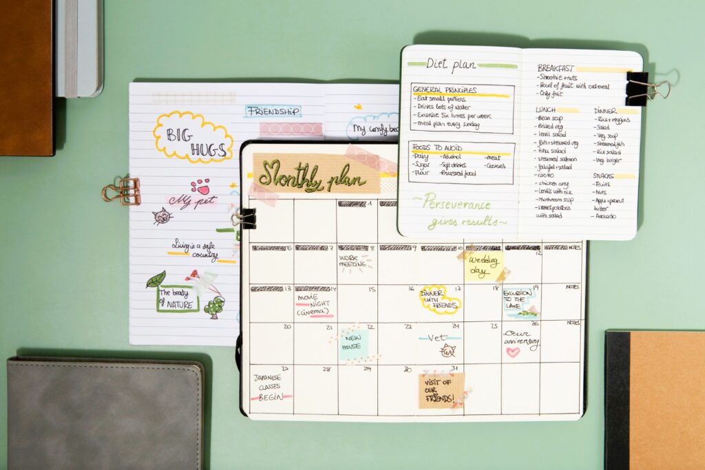 A flat lay of a colorful monthly planner with handwritten notes, meal plans, and to-do lists, showcasing the importance of organization and goal setting for a productive and fulfilling life