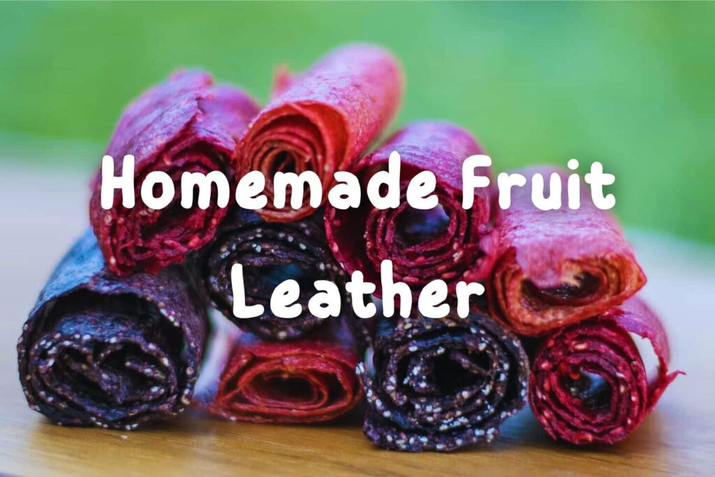 Close-up of homemade red fruit leather rolled up on a wooden cutting board.